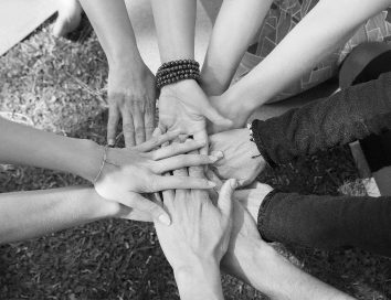 top-view-stack-hands-against-green-grass